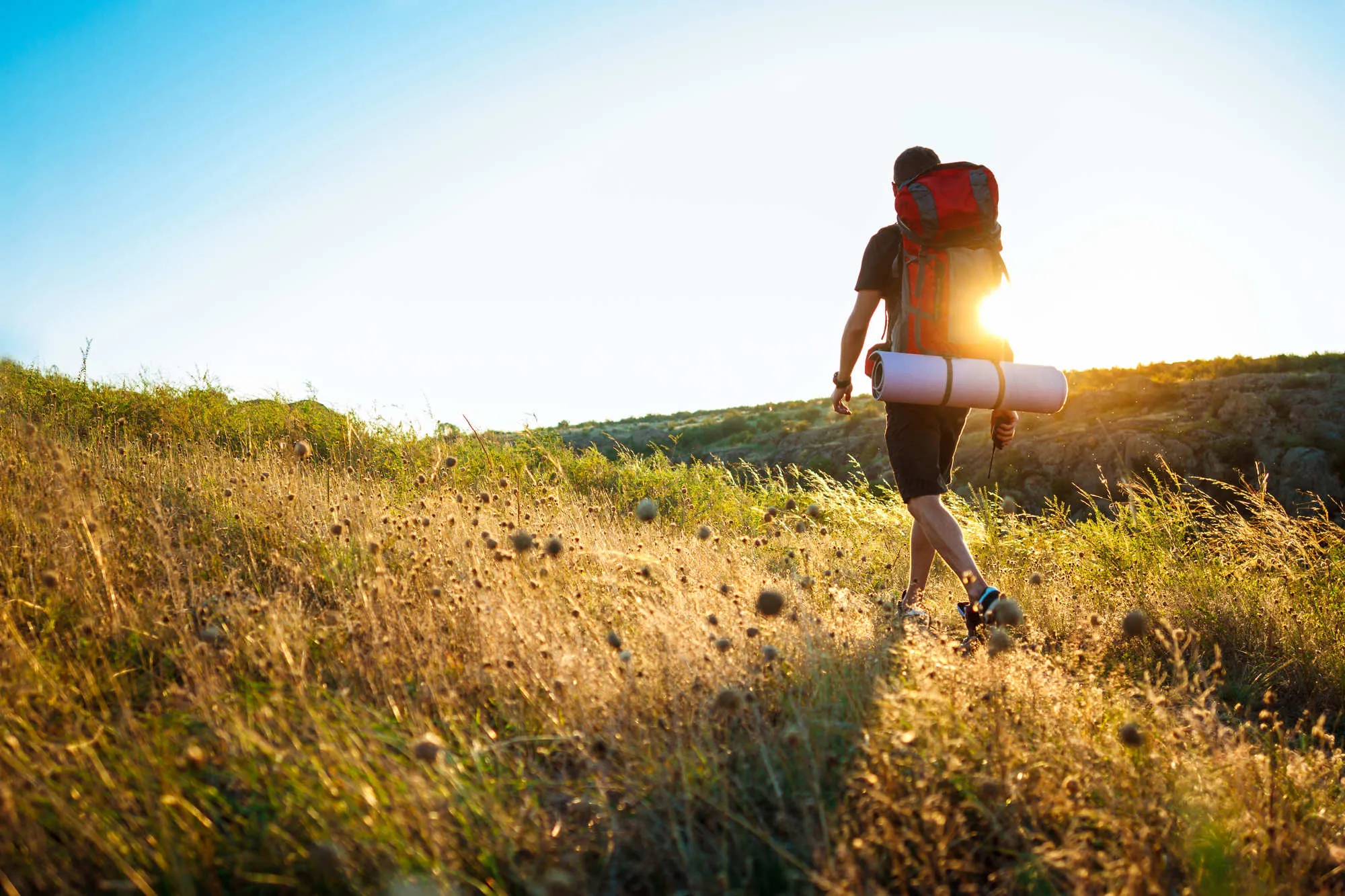 Young handsome man with backpack traveling in canyon at sunset.